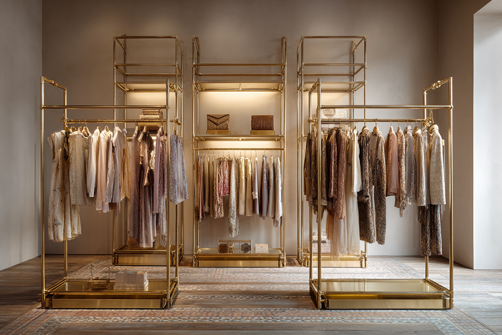 Interior of a luxury boutique with soft lighting and gold structures displaying refined garments and handbags—capturing the quiet elegance and craftsmanship of true luxury.